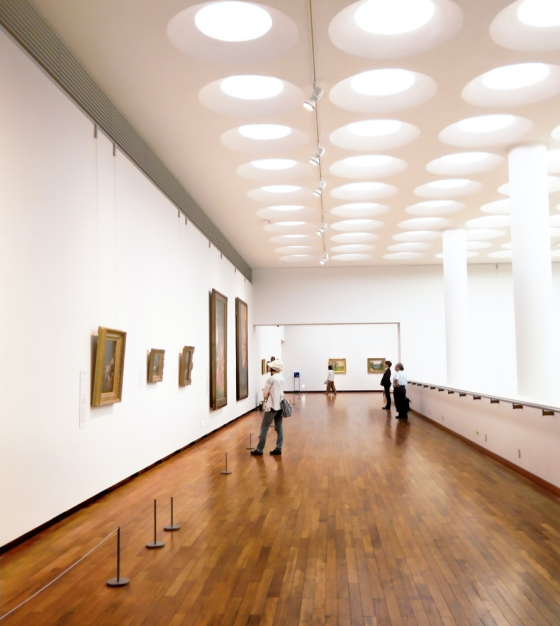 Gallery with circular ceiling lights and visitors viewing artwork